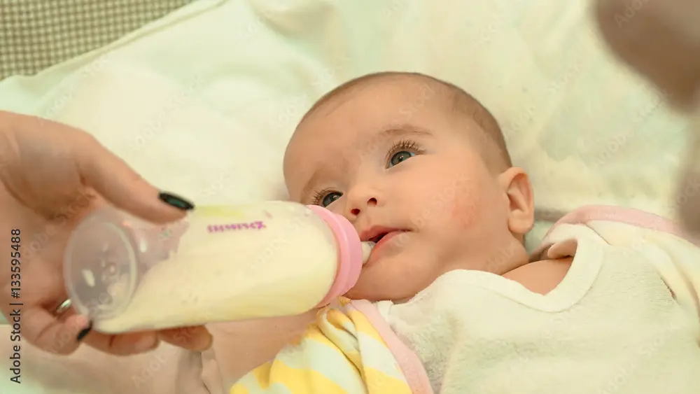 Bayi tersenyum bahagia sedang minum susu dari botol susu