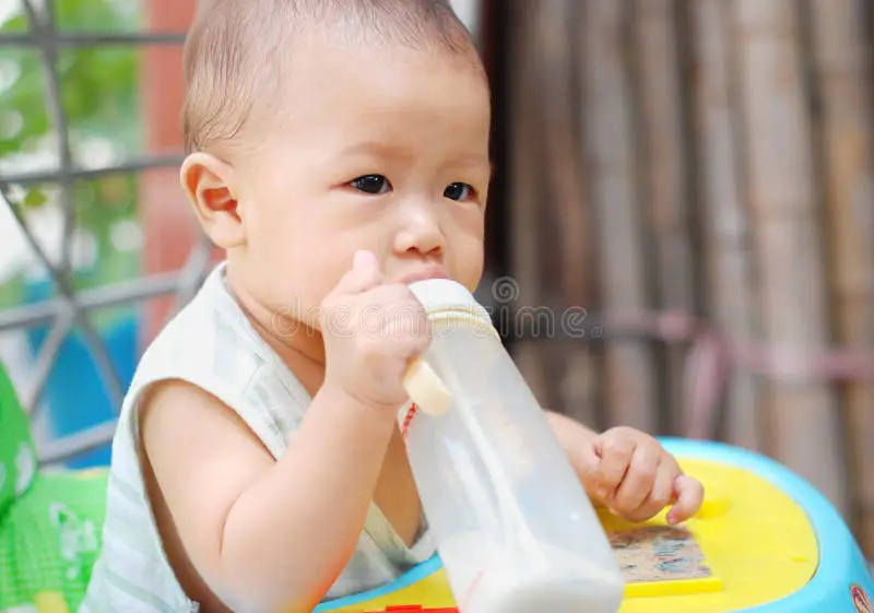 Gambar bayi yang sehat dan gembira sedang minum susu