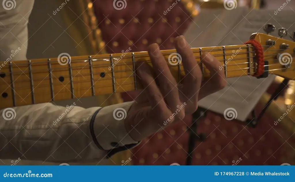 Gambar tangan sedang memainkan chord gitar