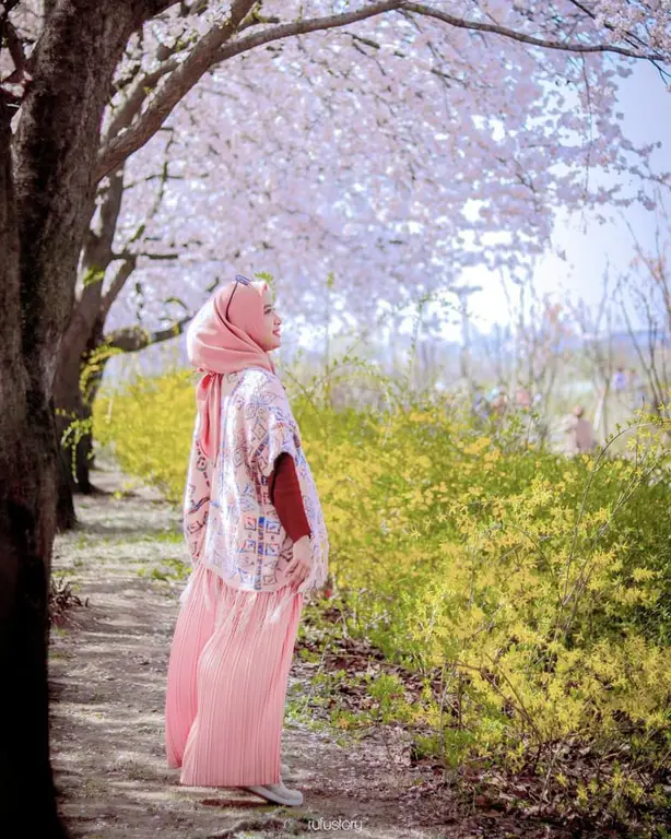 Wanita berhijab dengan latar belakang bunga sakura