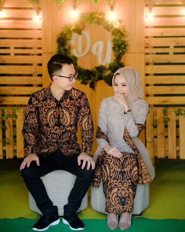 Pasangan tunangan mengenakan kebaya couple hijab dalam sesi pemotretan.