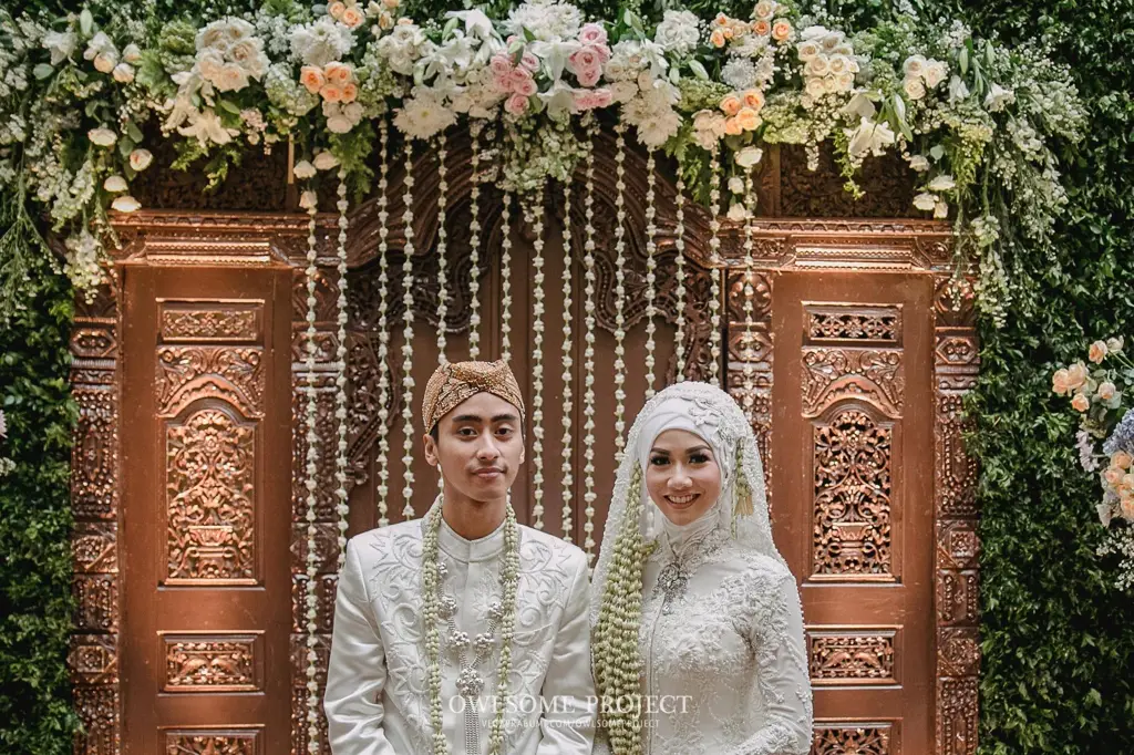 Pasangan pengantin Sunda mengenakan pakaian adat dengan hijab