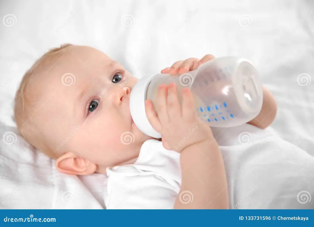 Bayi yang sehat dan gembira sedang minum susu