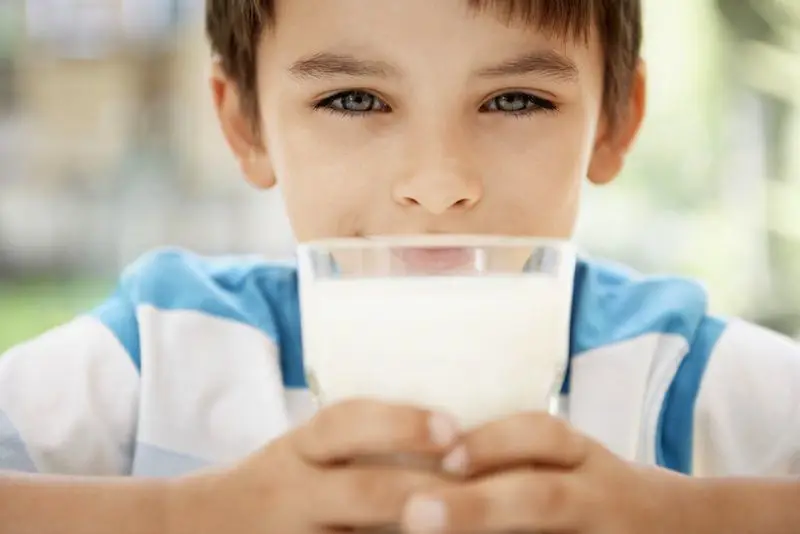 Anak yang gembira sedang minum susu Bantal