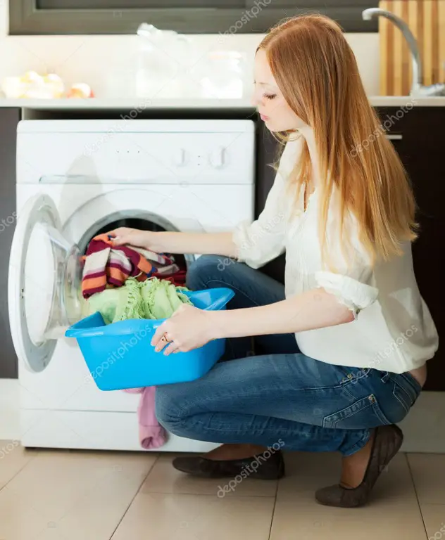 Wanita sedang menggunakan Mesin Cuci Aqua