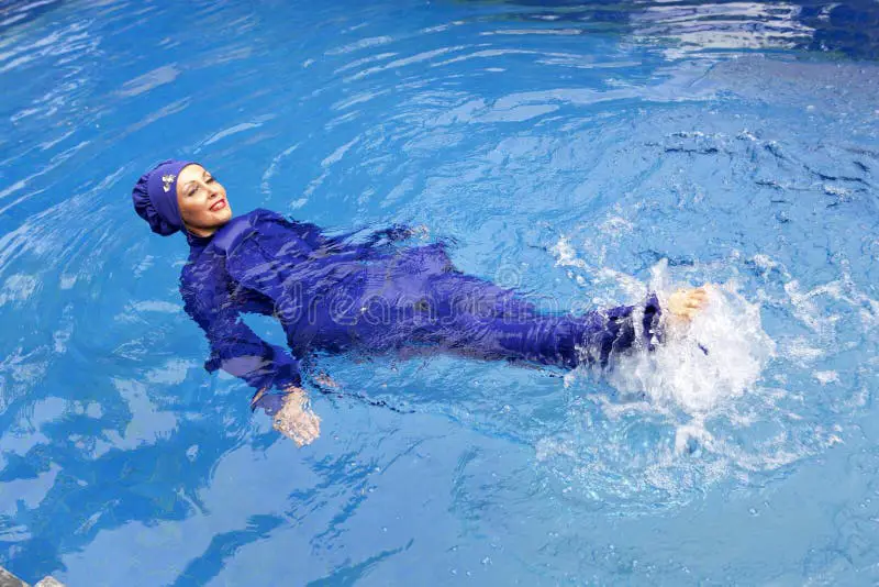 Wanita mengenakan burkini sedang berenang di pantai