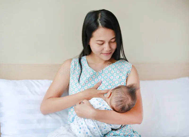 Ibu menyusui bayi di tempat tidur