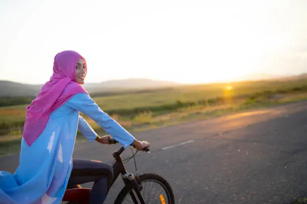 Wanita berhijab mengendarai motor dengan helm yang nyaman