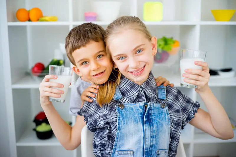 Anak yang gembira sedang minum susu