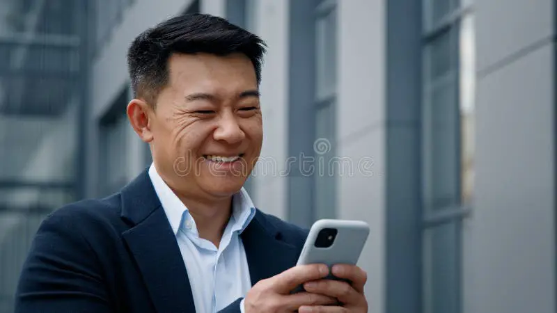 Gambar seorang pebisnis Korea yang sedang menggunakan smartphone untuk mengecek waktu.