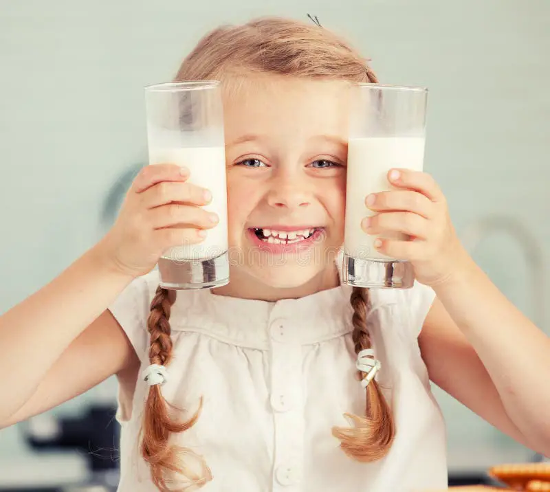 Anak yang gembira sedang minum susu