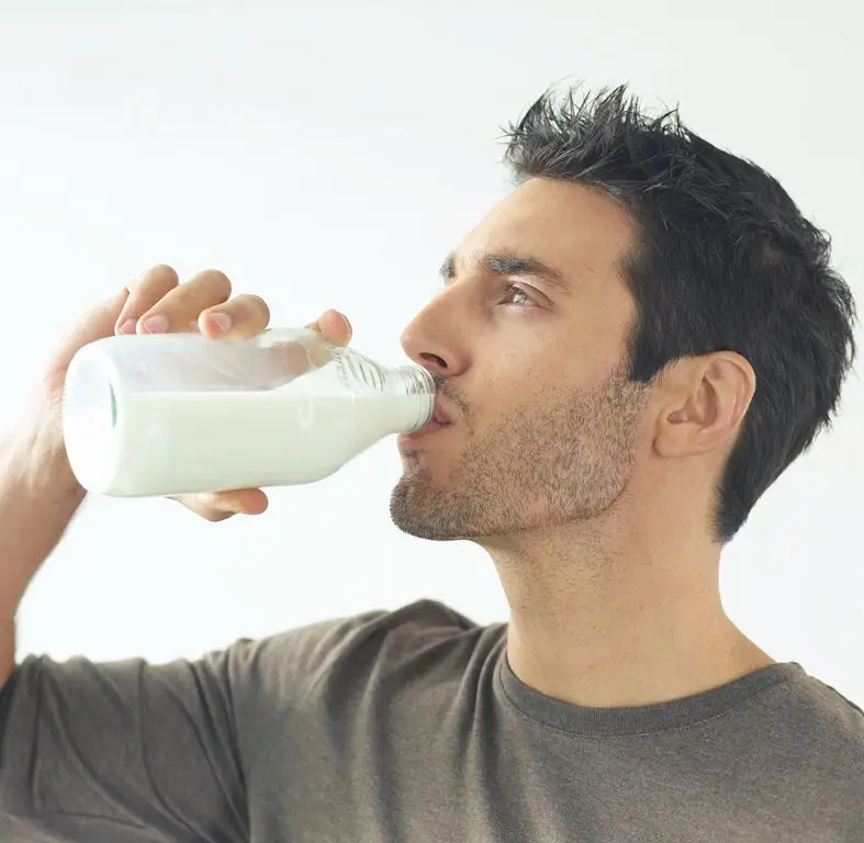 Seorang yang sedang minum susu setelah vaksinasi.