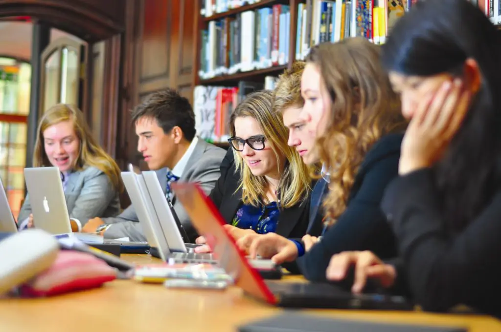 Mahasiswa yang sedang mengerjakan tugas di laptop