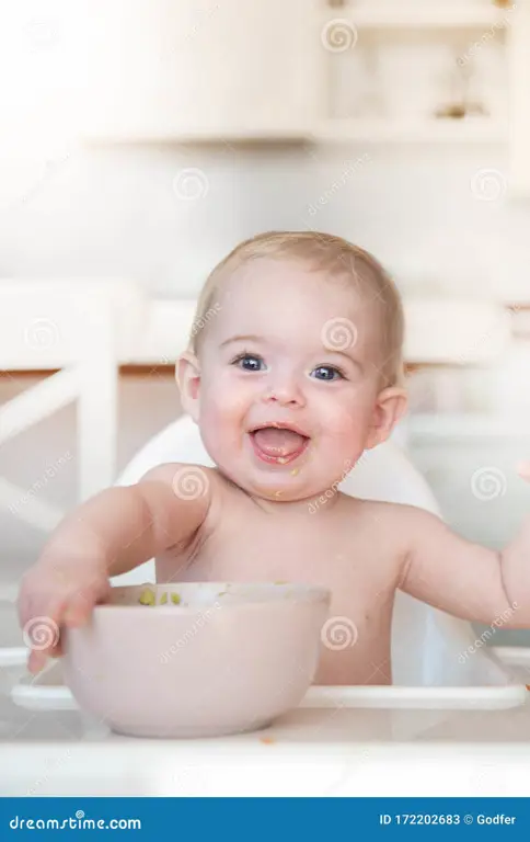 Bayi sehat dan gembira sedang makan makanan bergizi