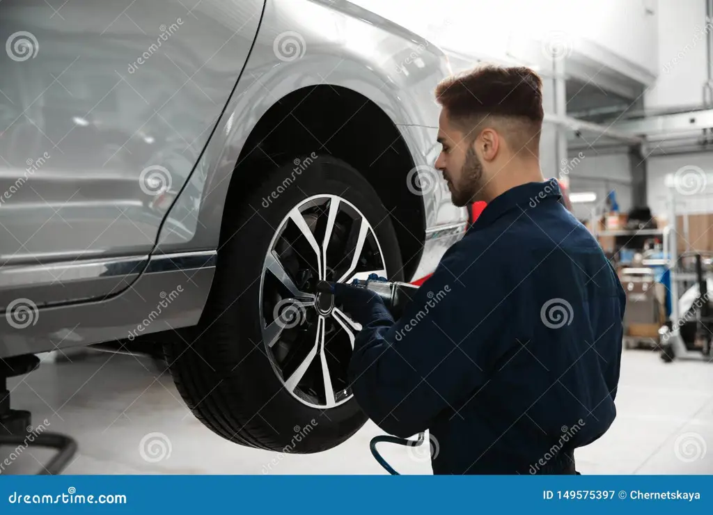 Teknisi sedang memperbaiki mobil, fokus pada detail kecil