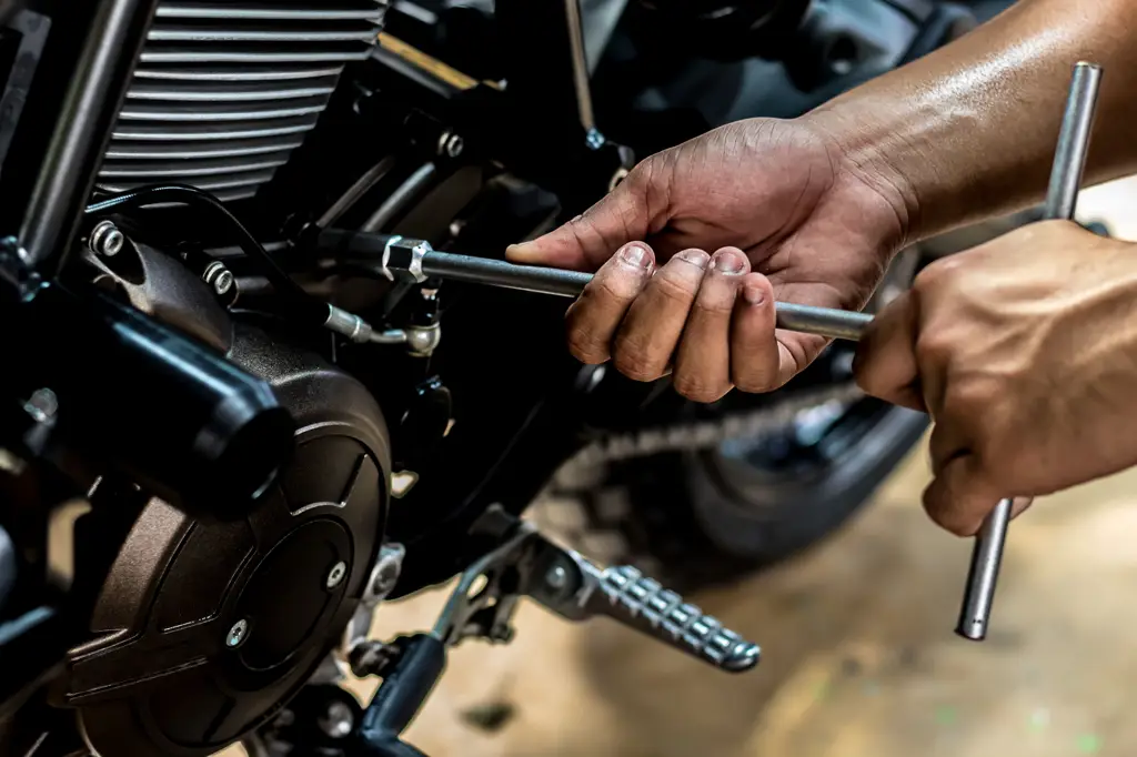 Mekanik sepeda motor sedang memperbaiki sepeda motor