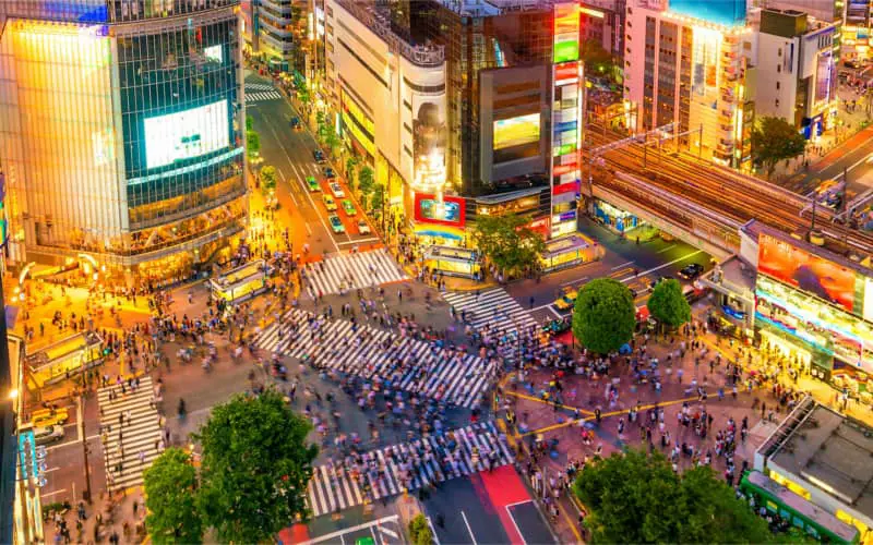 Persimpangan Shibuya di malam hari yang ramai dan penuh cahaya