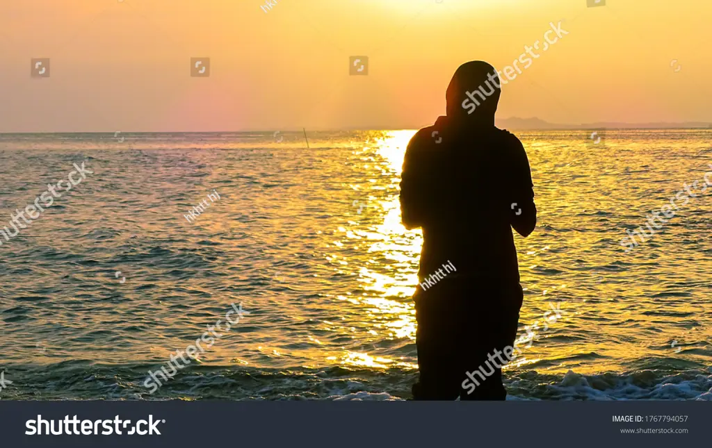 Siluet wanita berhijab di pantai yang indah