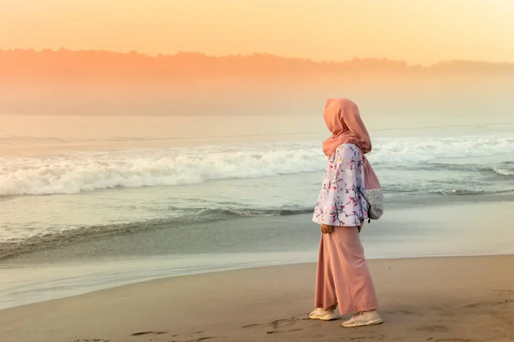 Wanita berhijab menikmati keindahan sunset di pantai