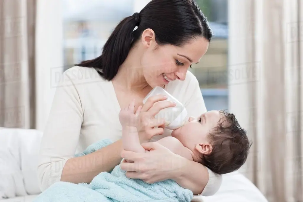 Ibu memberi makan bayi dengan botol susu