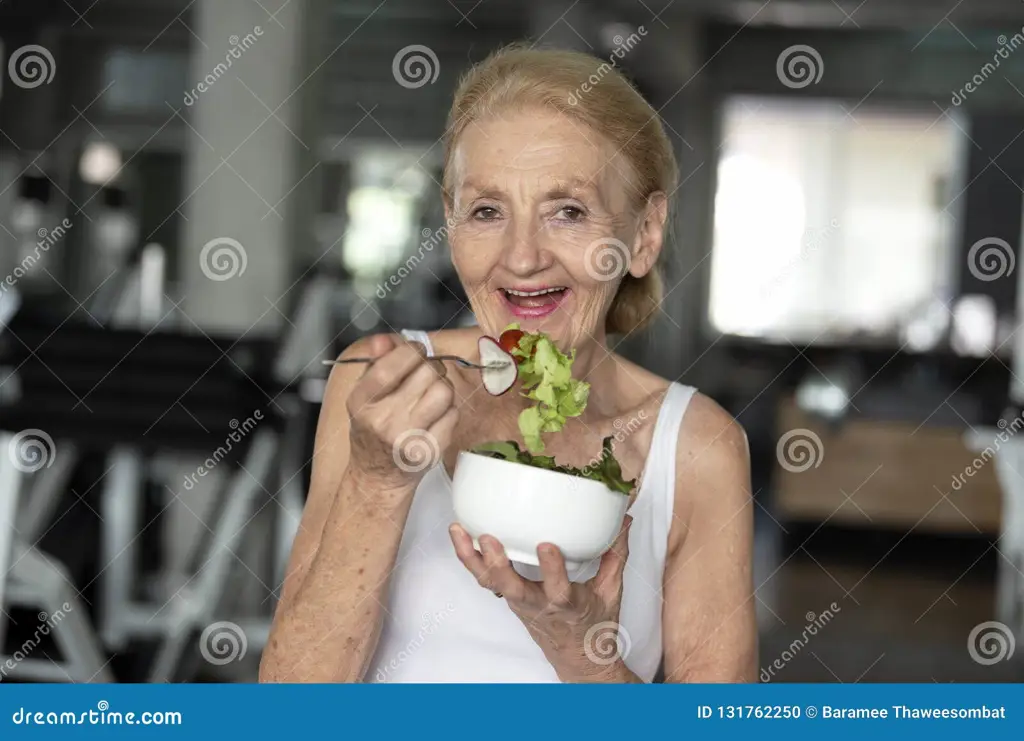 Seorang wanita lansia sedang makan makanan sehat