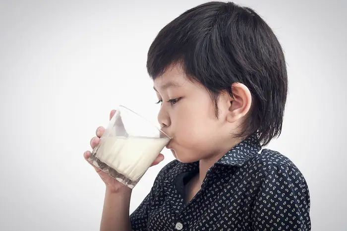 Anak sedang minum susu untuk tumbuh kembang