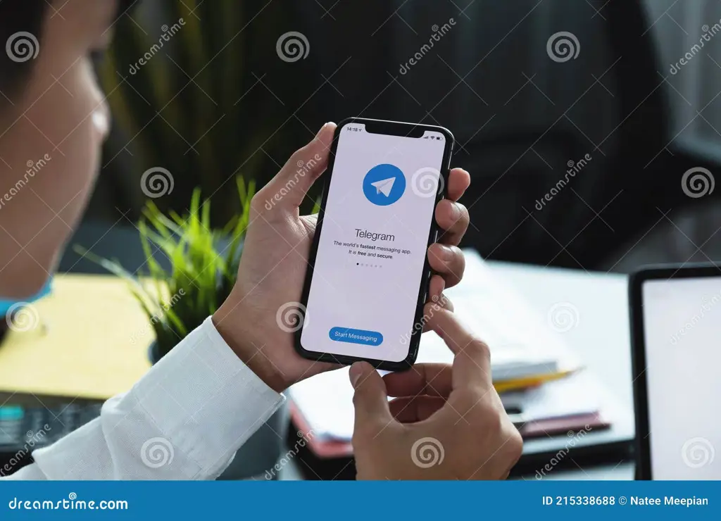 Tangan memegang telepon pintar yang menampilkan aplikasi Telegram.