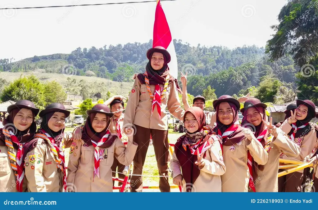 Para siswa SMA pramuka sedang mendaki gunung dengan tongkat mereka